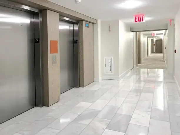 Corredor de prédio com portas de elevador em inox